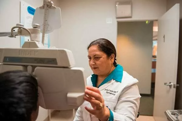 dr. tandon examining a young patient's vision with medical equipment