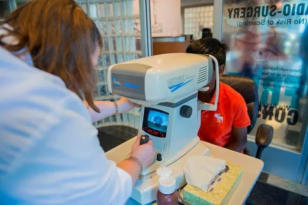 medical assistant checks a young boy's vision with medical equipment