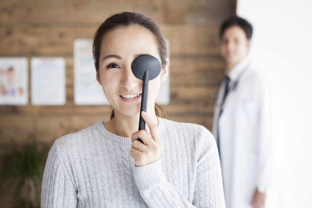 Woman covering eye during eye exam