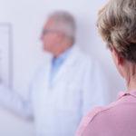 Woman reading from a Snellen eye chart during eye exam.