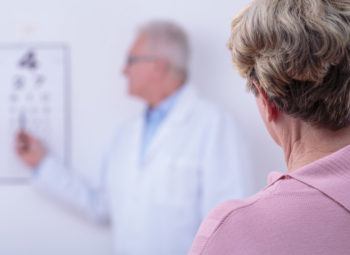 Woman reading from a Snellen eye chart during eye exam.