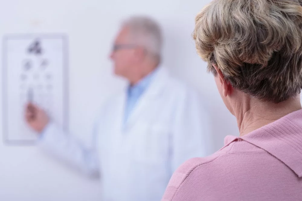 Woman reading from a Snellen eye chart during eye exam.