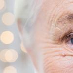 half of elderly womans face with speckles of light behind her head