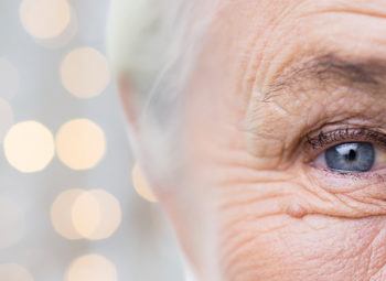 half of elderly womans face with speckles of light behind her head