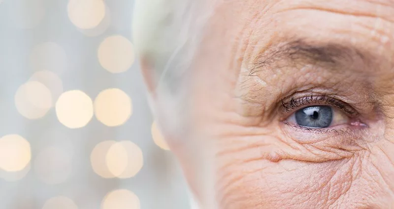 half of elderly womans face with speckles of light behind her head