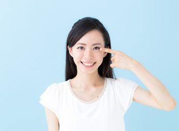 young asian woman point at her eye with her finger