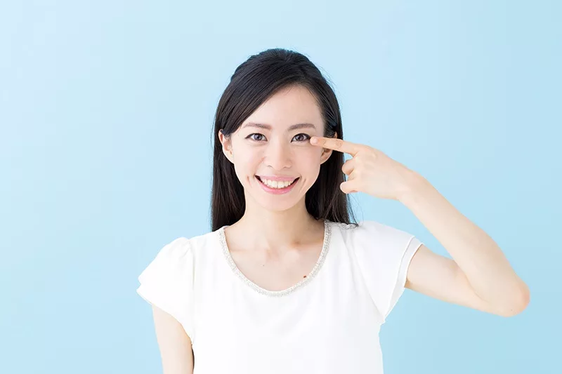 young asian woman point at her eye with her finger
