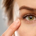 close up of a women's face pointing a finger to her green eye