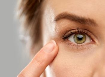 close up of a women's face pointing a finger to her green eye