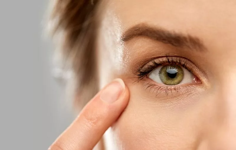 close up of a women's face pointing a finger to her green eye