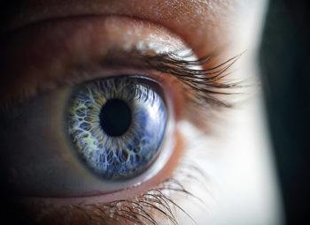 Close up or a blue eye looking off camera with a black background