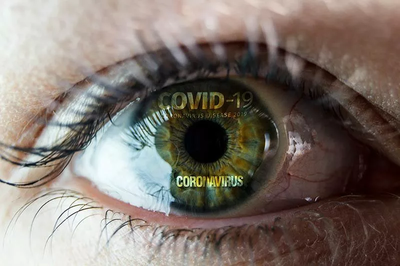 close up of eye with the worlds covid-19 and coronavirus reflected in it