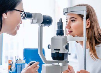 an ophthamologist or optometrist examines the eye health of a female patient