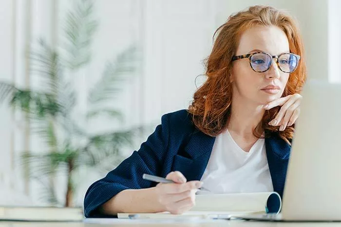 women in eyeglasses on laptop researching LASIK surgeons