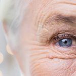 half of elderly womans face with speckles of light behind her head