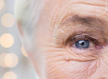 half of elderly womans face with speckles of light behind her head