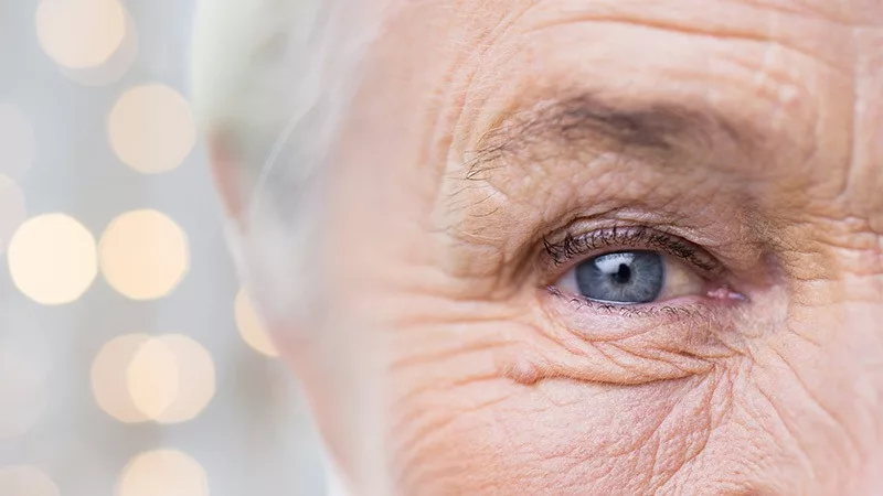 half of elderly womans face with speckles of light behind her head