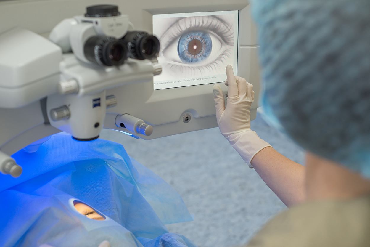 gloved hand hovering over Lasik display filled with image of patient's eye