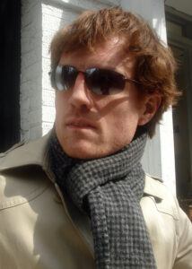 man in coat and knit scarf wearing sunglasses