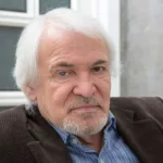 Head shot of gray-haired man in dress shirt, sports coat. Right eye has cataract.