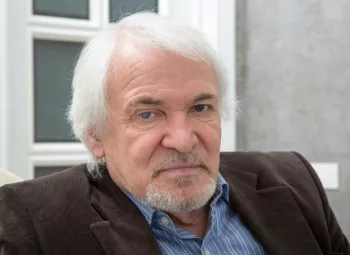 Head shot of gray-haired man in dress shirt, sports coat. Right eye has cataract.