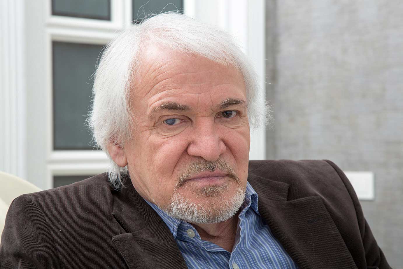 Head shot of gray-haired man in dress shirt, sports coat. Right eye has cataract.