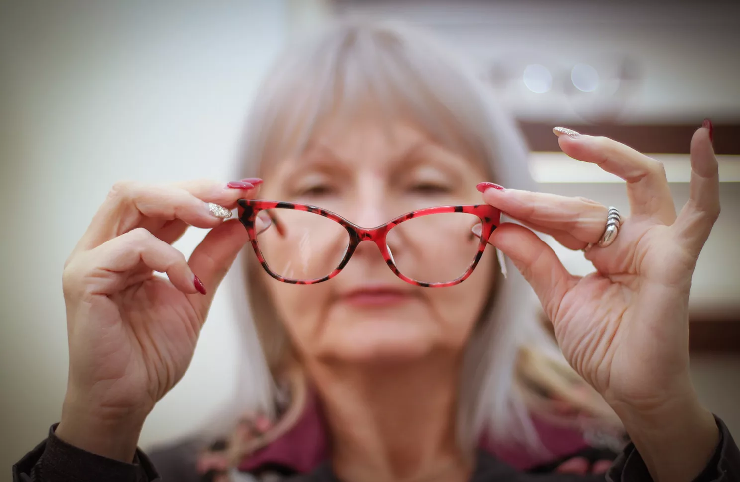Senior woman holding glasses out from her face.