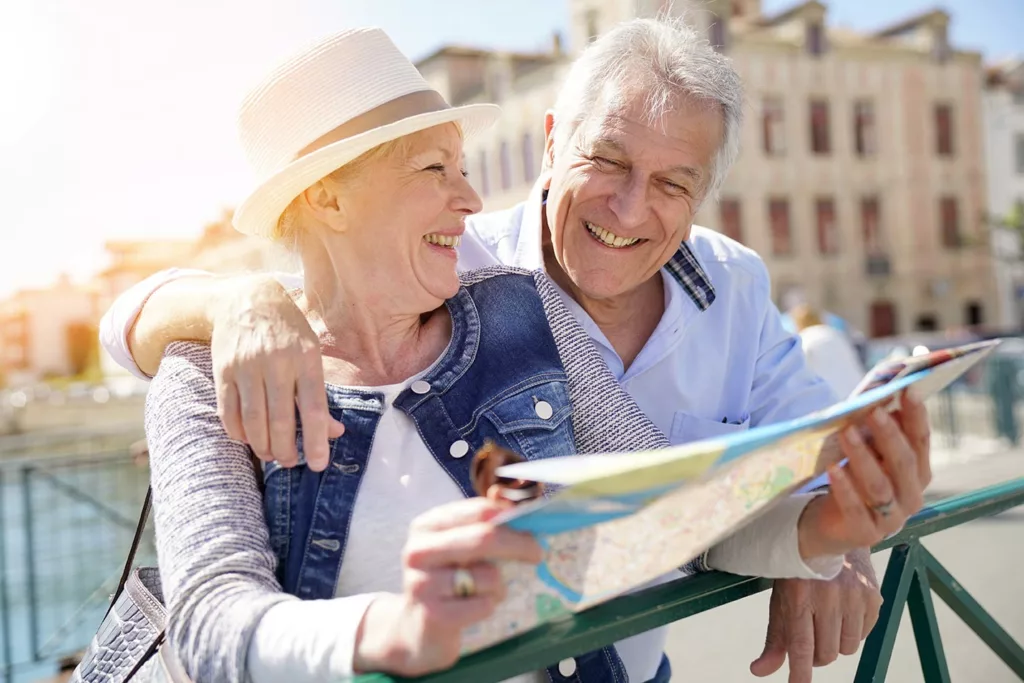 senior couple smiling and looking at map in sunshine
