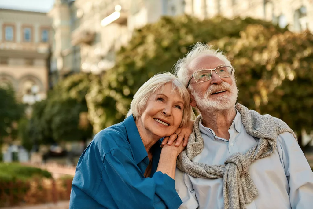 Smiling senior couple looking above. He has glasses, she does not. 