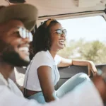 Young smiling couple wearing glasses in front seat on a road trip.