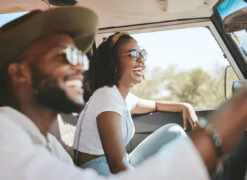 Young smiling couple wearing glasses in front seat on a road trip.