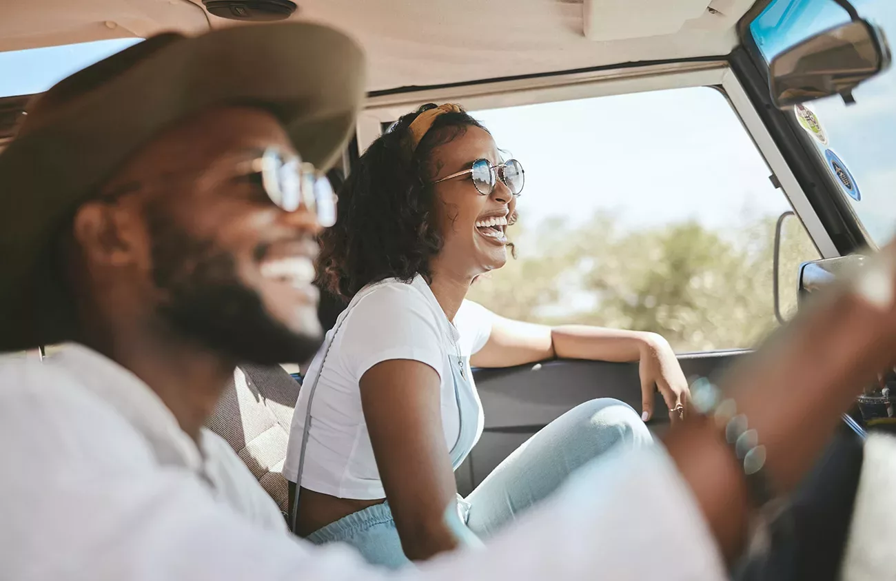 Young smiling couple wearing glasses in front seat on a road trip.