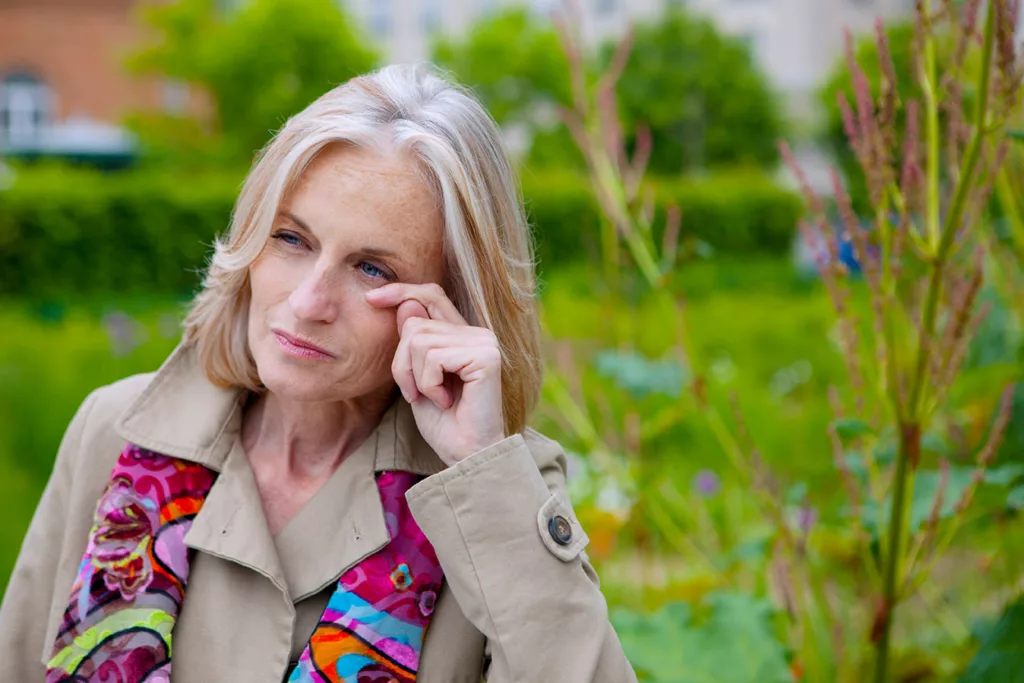 Middle ages women in a park with watery eyes from seasonal allergies