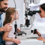 A dad taking his daughter to get an exam at the eye doctor.