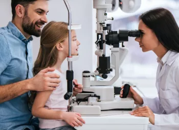 A dad taking his daughter to get an exam at the eye doctor.