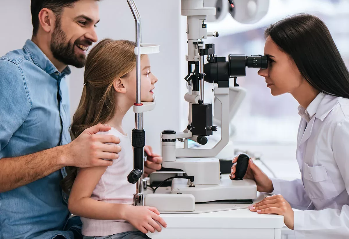 A dad taking his daughter to get an exam at the eye doctor.