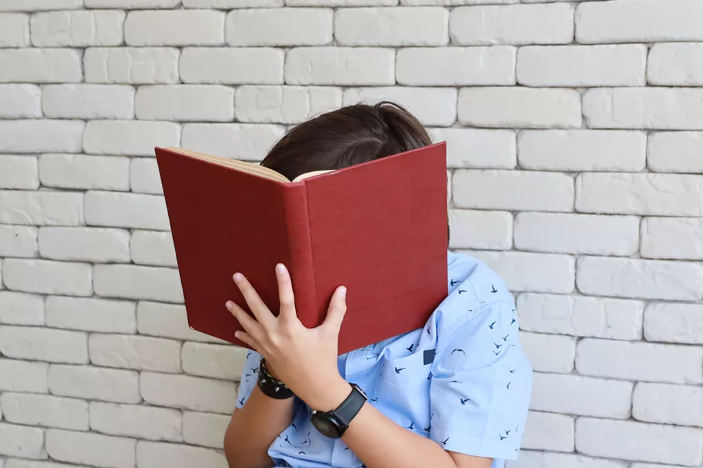 A nearsighted child holds a book close to his face so he can read more clearly.