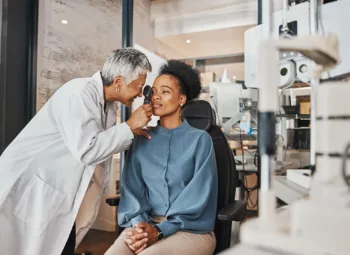 A woman tells an eye doctor about her symptoms while getting an exam.