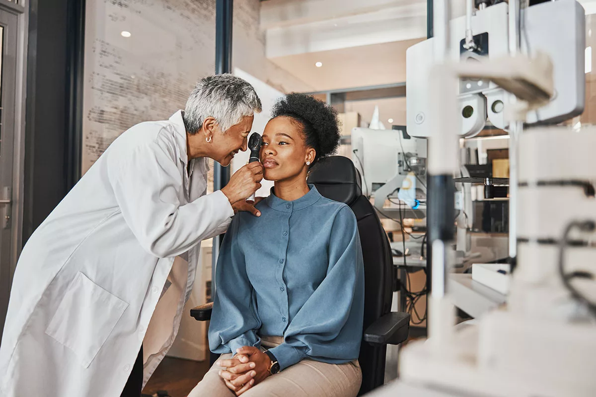 A woman tells an eye doctor about her symptoms while getting an exam.