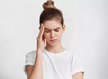 A portrait of a tired young woman rubbing her temples due to an ocular migraine