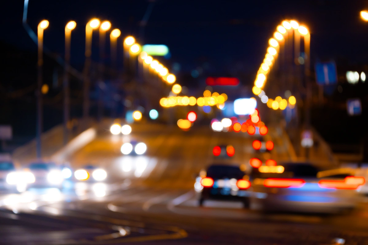 City traffic at night appearing very blurry with bright halos around all the lights depicting poor vision at night caused by night blindness