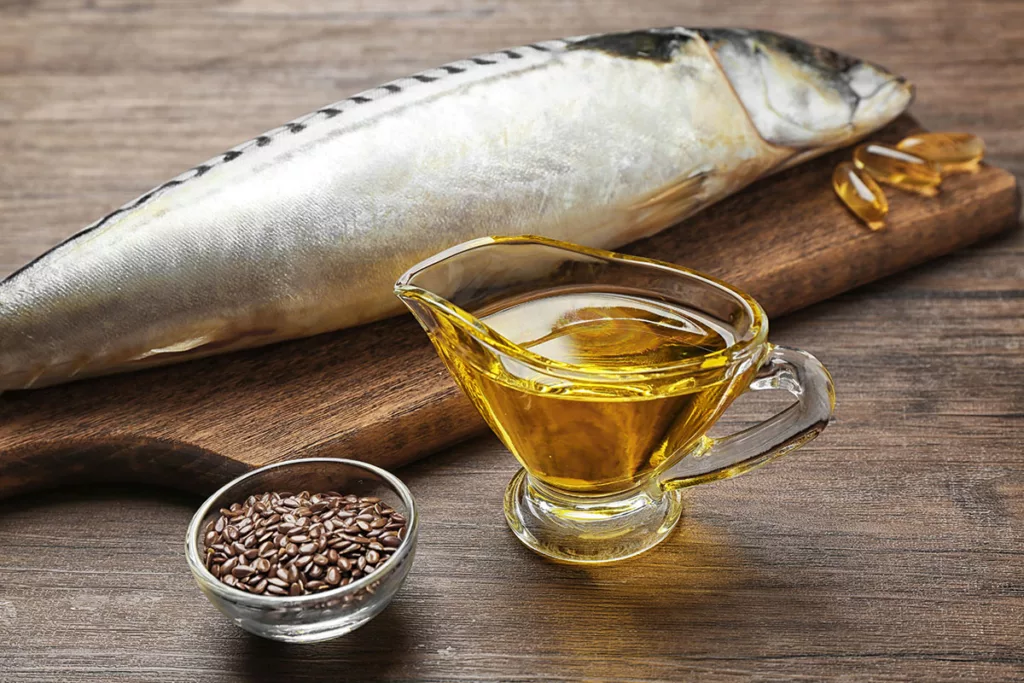 A dish of fish oil with vitamin A and a gray fish against a wooden background